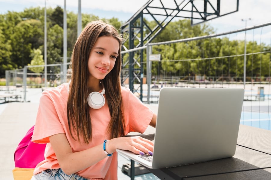 A young school girl doing homework on her laptop.
