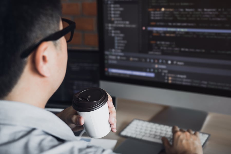 A programmer working on codes while drinking coffee.
