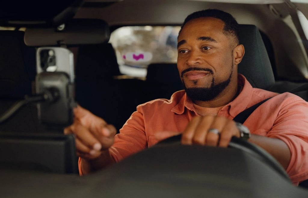 Man driving car, interacting with a smartphone on a dashboard mount