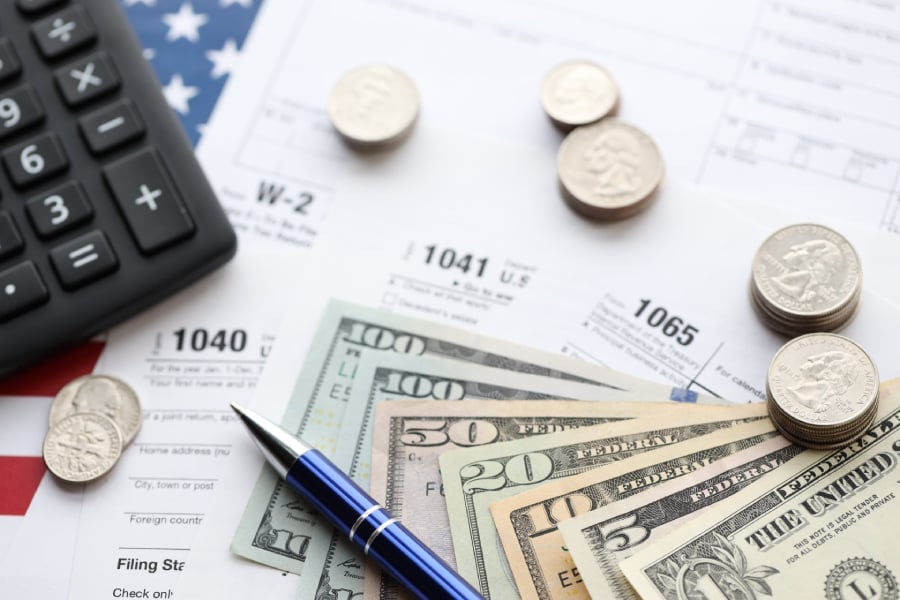 Dollar bills and coins with pen and calculator and several documents.