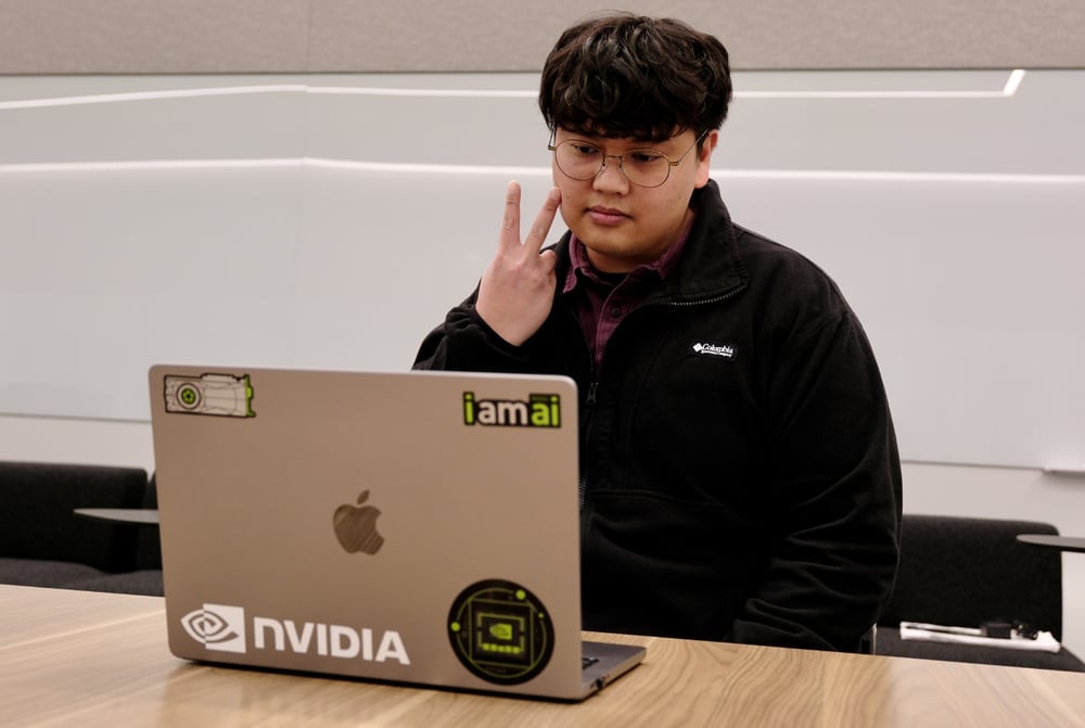 Young male teen learning sign language on laptop.