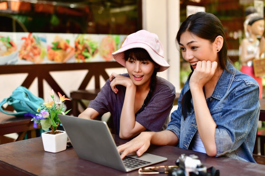 2 asian-looking girls using a laptop.