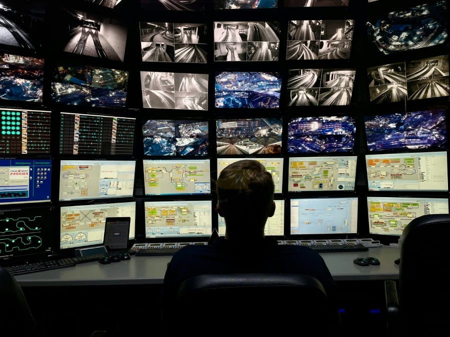 A man sitting in front of multiple security monitors.