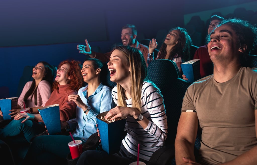 Group of people laughing while watching a movie.