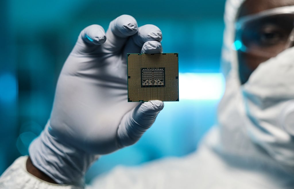 Man in protective suit and gloves holding a processing chip.