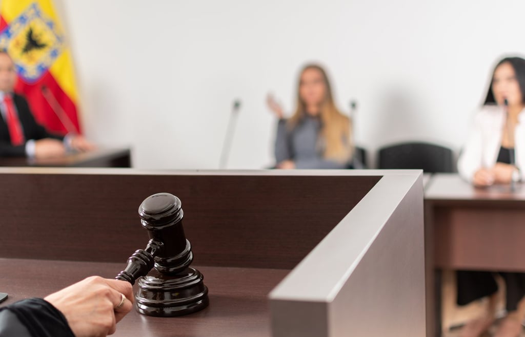 Close up shot of a judge's hand with a gavel in a court room hearing.