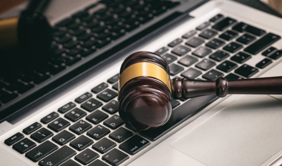 A judge's gavel placed on top of a laptop.