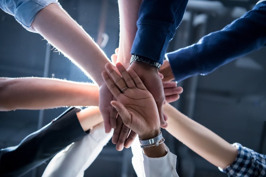 A group of people on a huddle and getting hands on deck as a sign of teamwork.