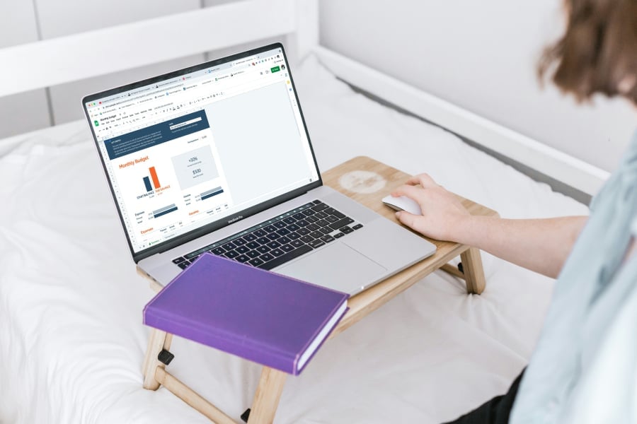 A person using a laptop on a bed.