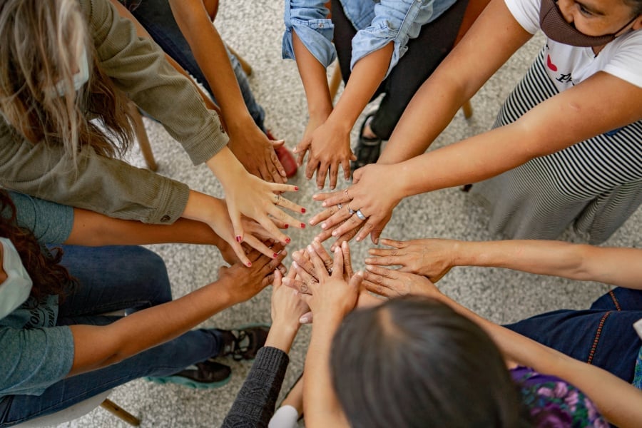 A group of people standing in a circle with their hands together.