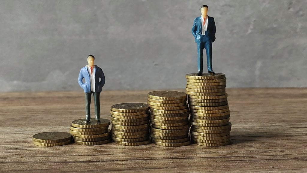 Miniature businessmen standing on stack of coins.