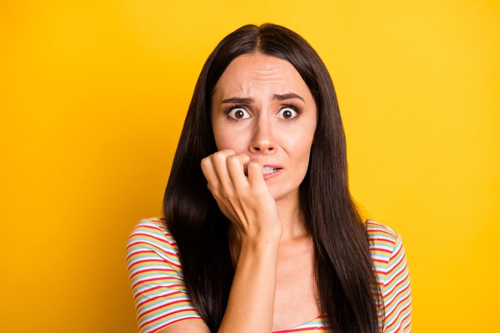 A shocked and afraid girl biting her nails.