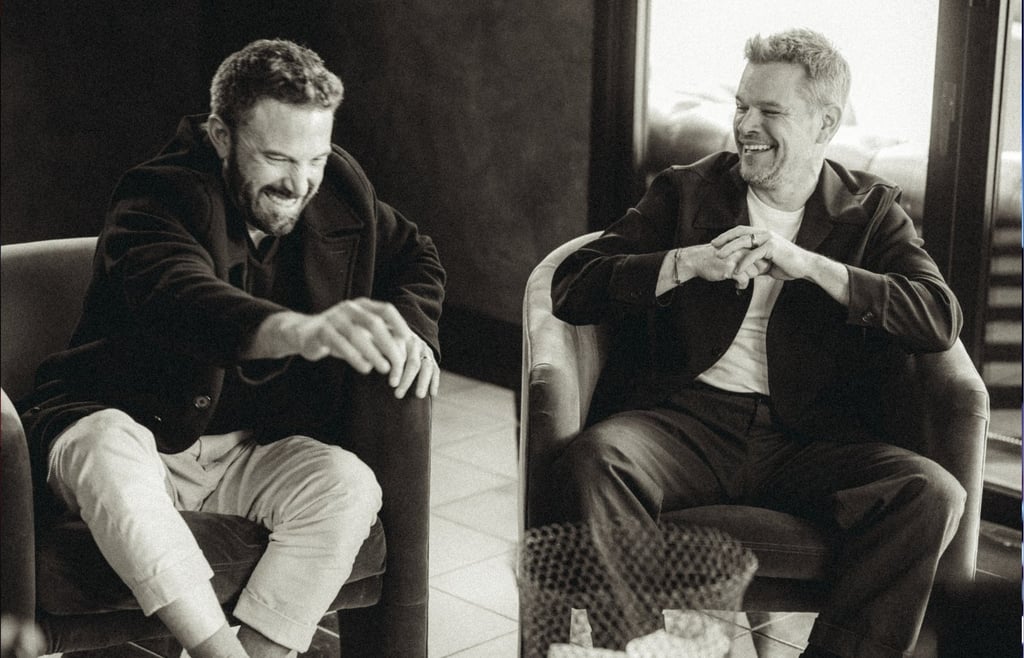 Black and white photo of actors Ben Affleck and Matt Damon laughing together during an interview