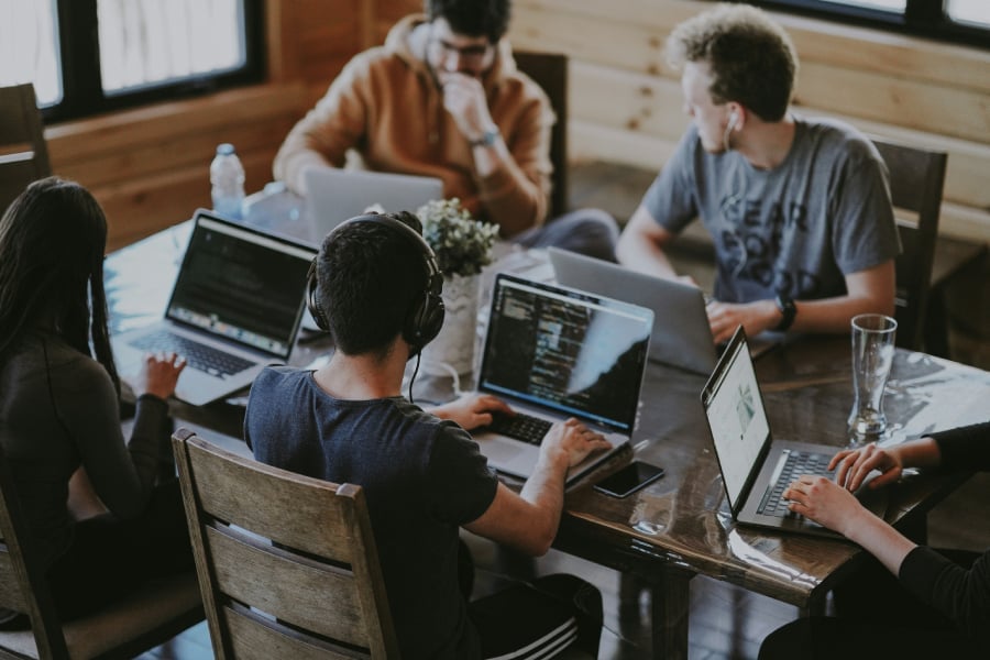 Group of people using laptop computer on a table.