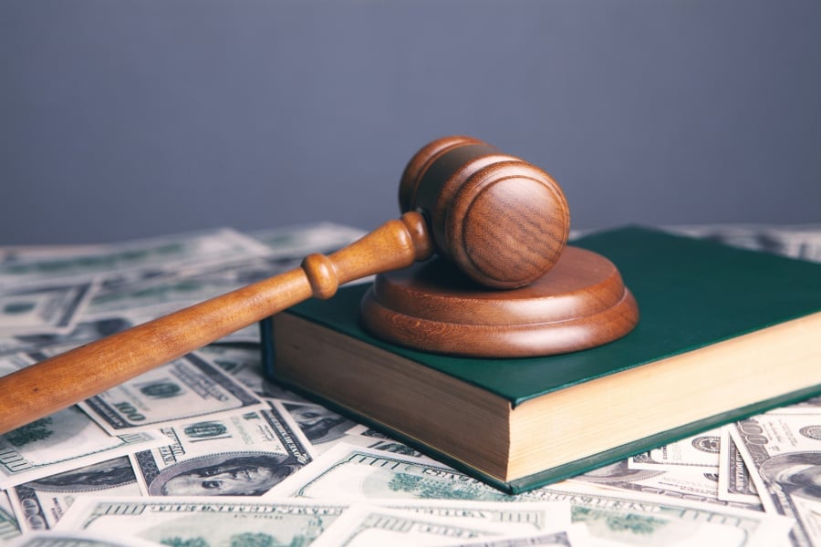 A judge's hammer on top of a book with bills.