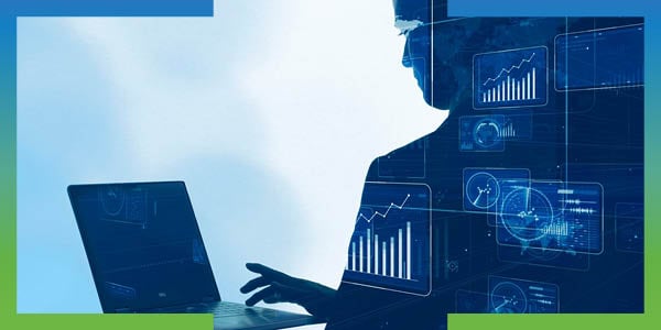 Silhouette of a businessperson typing on a laptop computer, with financial charts overlaid on the image