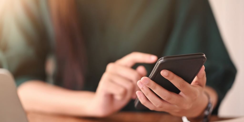 Close up shot person using a smartphone on wood table.