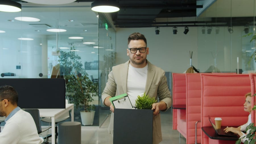 Man carrying box of belongings in office.