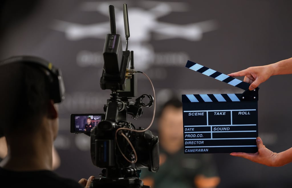 Back view of a cameraman and a hand holding a board clapper.