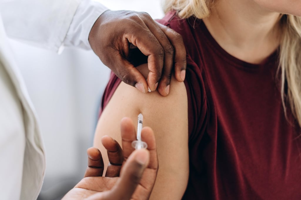 Close up of doctor vaccinating woman in clinic.