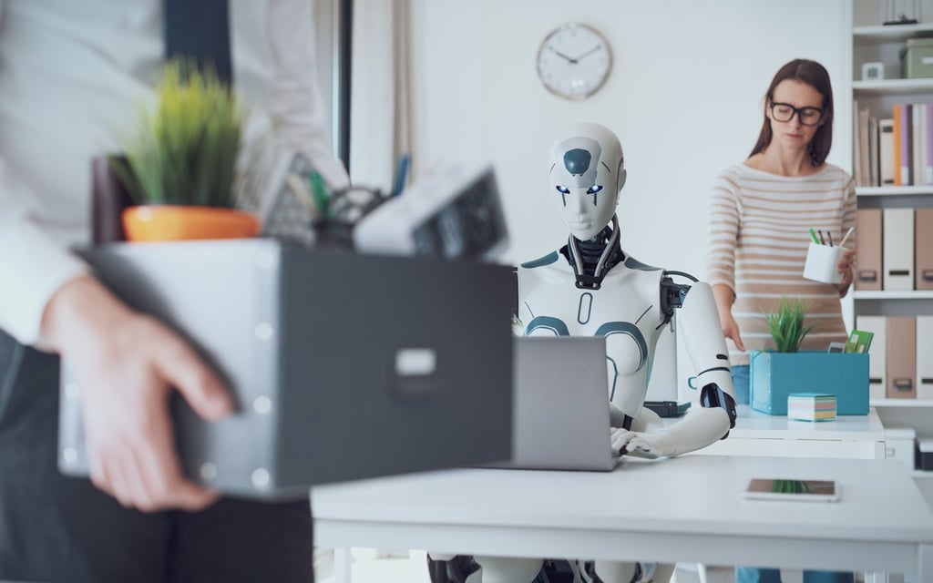 Dismissed business people packing their belongings and leaving the office, a robot is sitting at the desk and working: the impact of AI on jobs