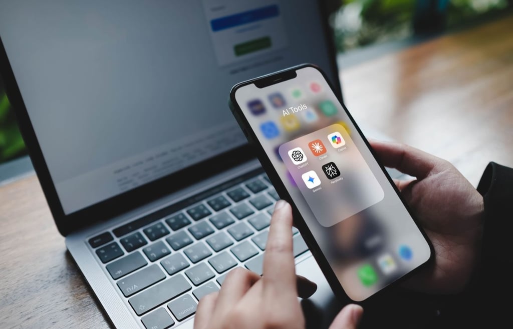 Hands holding an iPhone with a folder open showing AI applications like Claude, Gemini, and Perplexity AI.