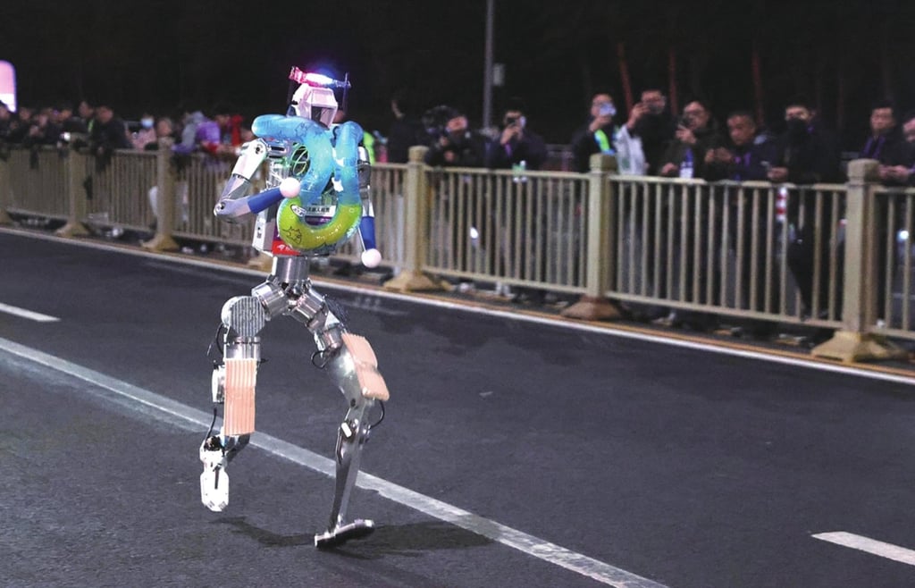 A humanoid robot running during a night test for the 2026 Beijing E-Town Half Marathon, with spectators watching from behind a fence.