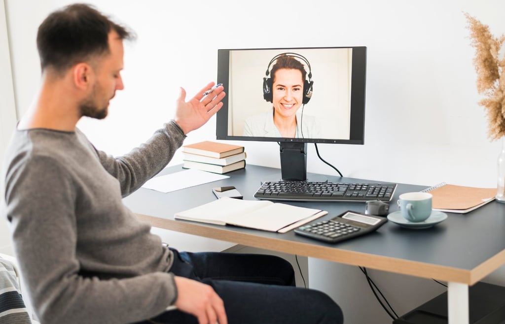 Man in a gray shirt on a video call with a woman wearing headphones.