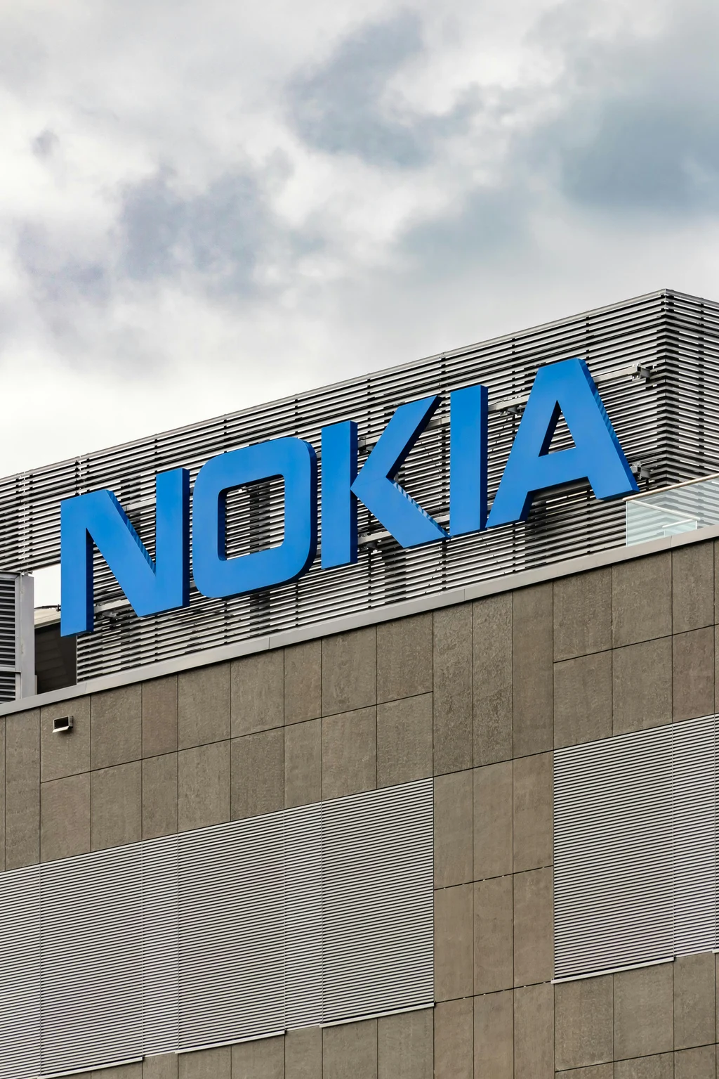 Nokia logo displayed on the exterior of a modern office building under a cloudy sky.