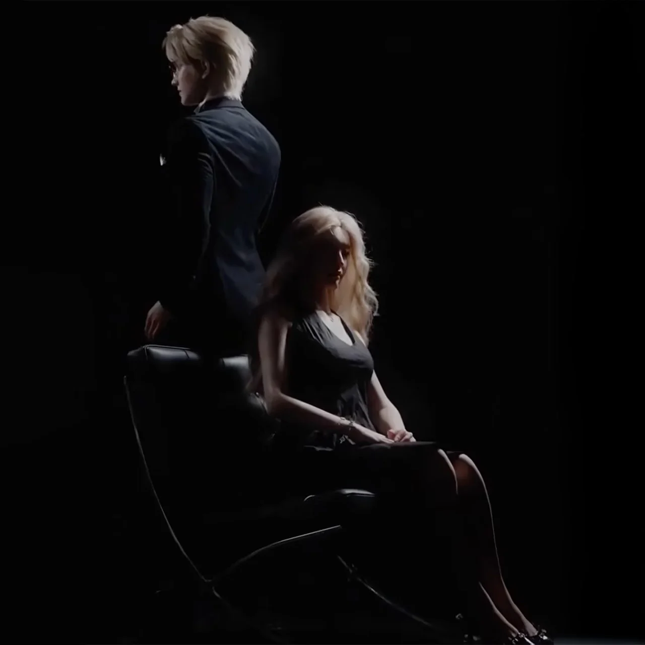 A woman siting behindi a humanoid robot.